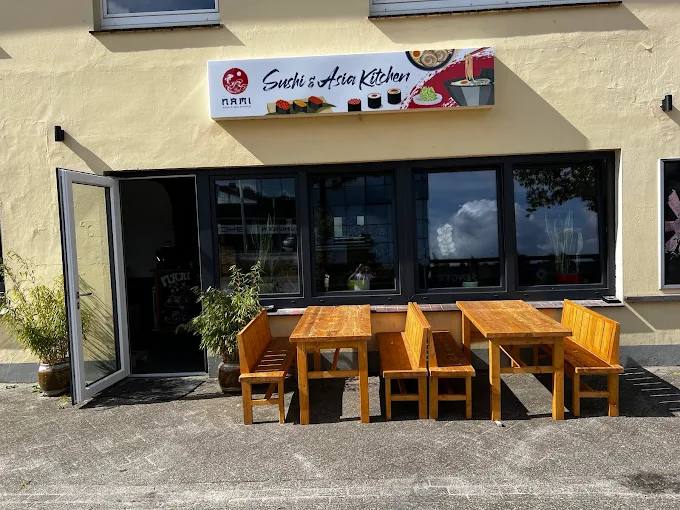 Außenansicht des Nami mit Schild „Sushi & Asia Kitchen“ und Sitzbänken vor dem Eingang