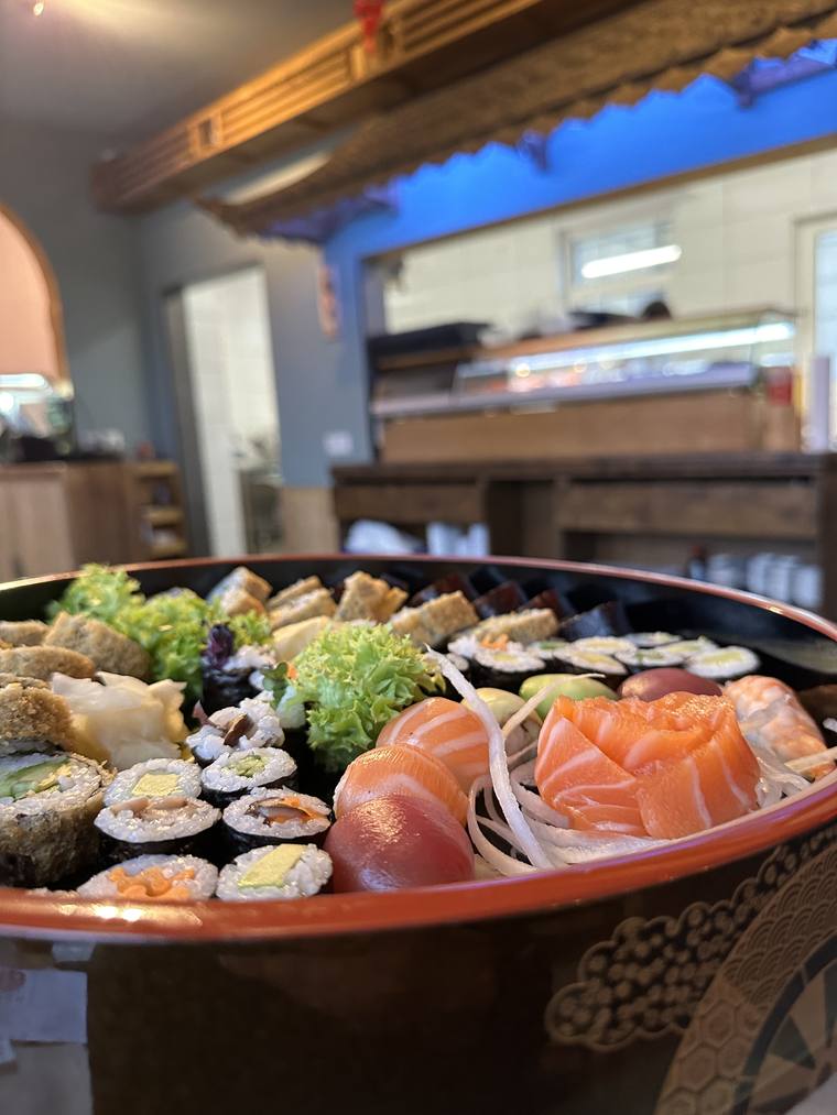 Große Sushi-Platte auf einem Tisch im Gastraum, im Hintergrund der Tresen