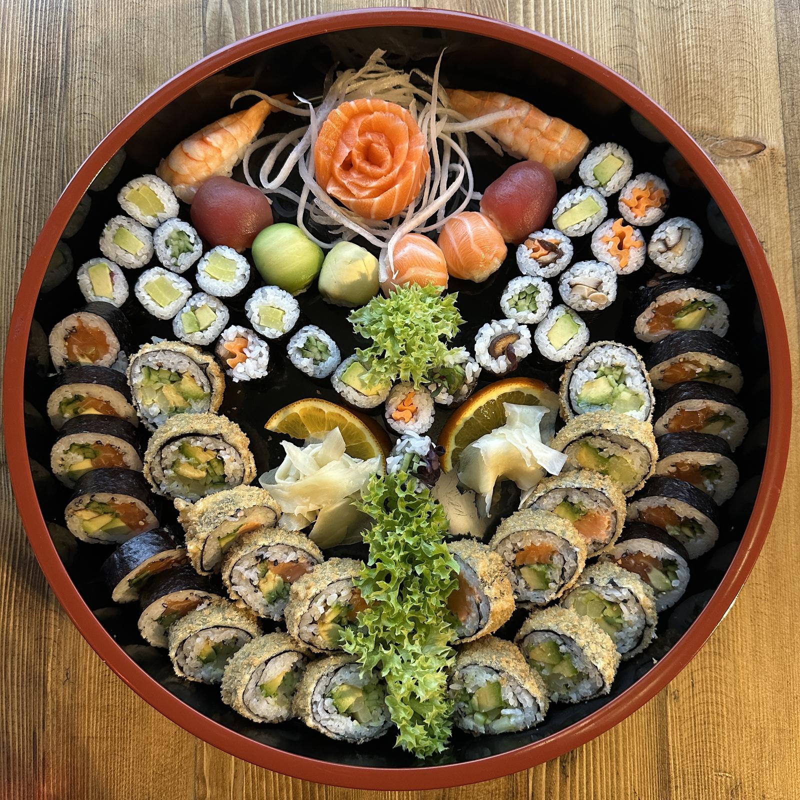 Runde Sushi-Platte mit Maki, Inside-Out-Rollen und einer Lachsrose in der Mitte