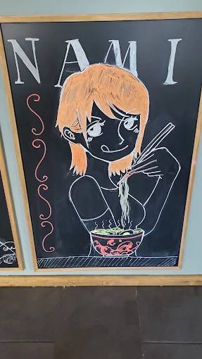Handgemaltes Tafelbild mit Nami-Schriftzug und einer Figur, die Ramen isst